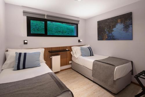 two beds in a small room with two windows at Hotel Alto Traful in Villa Traful