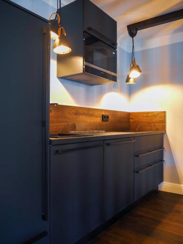 a kitchen with blue cabinets and a microwave and lights at Design Hotel ALPENLIEBE - - - - Boutique-Flair - - - - in Inzell