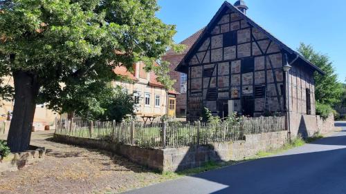 um antigo edifício de madeira ao lado de uma cerca em Ferienwohnung Alte Dorfschule em Witzenhausen