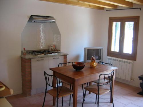 y cocina con mesa de madera, sillas y fogones. en Villa Pastori, en Mira