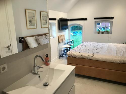 a bathroom with a sink and a bed and a tub at Saromaja B&B in Ambt Delden