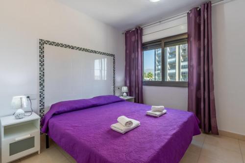 a bedroom with a purple bed with two towels on it at Bahia del Sol in Calpe