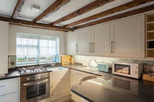 a kitchen with white cabinets and a sink and a microwave at Barnaby's Lodge in Broadstairs - Exclusive unmissable deals! Book now before it's too late! in Broadstairs