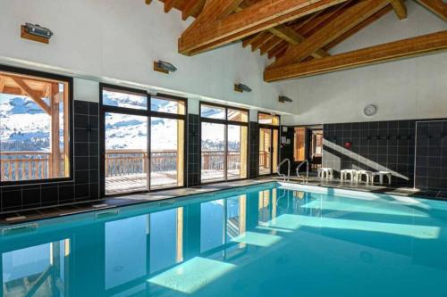 - une piscine d'eau bleue dans une chambre avec fenêtres dans l'établissement Vue panoramique sur les montagnes plein Sud - T2 Skis aux pieds, Piscine & Spa, à Flaine