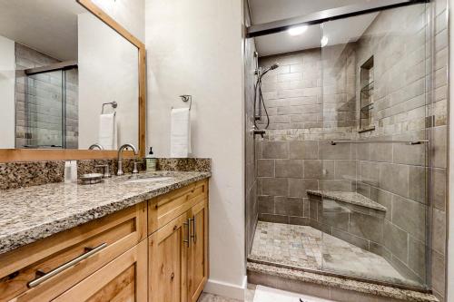 uma casa de banho com um chuveiro, um lavatório e uma cabina de duche em vidro. em Après Adventure em Steamboat Springs