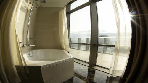 Parkside Hotel & Apartments في باكو: حمام مع حوض استحمام ونافذة