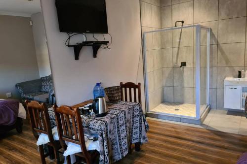 a dining room with a table and a glass shower at Pattys Place 12 Hakbos Street in Kathu