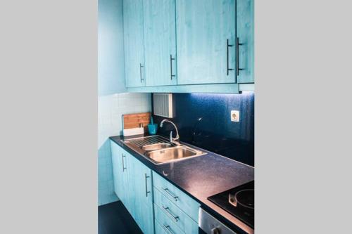 a kitchen with blue cabinets and a sink at REFÚGIO LOURO • gym - pool - tennis in Leça da Palmeira