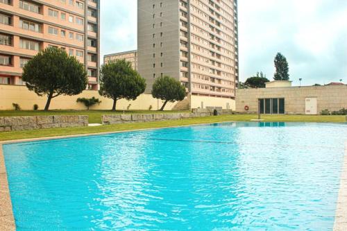 a blue swimming pool in front of some buildings at REFÚGIO LOURO • gym - pool - tennis in Leça da Palmeira