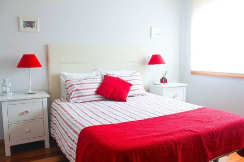 een slaapkamer met een rood en wit bed met 2 lampen bij REFÚGIO LOURO • gym - pool - tennis in Leça da Palmeira