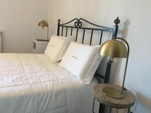 a bed with white pillows and a table with a lamp at Quinta da Corga in Prova