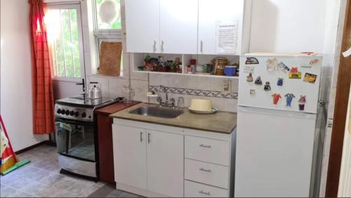 uma cozinha com um frigorífico branco e um lavatório em Preciosa casa en la tranquilidad de Colonia Relájate con toda la familia donde la tranquilidad se respira - A una cuadra de la mejor zona de la rambla de Colonia del Sacramento te espera esta casa para pasar las vacaciones en familia em Colônia do Sacramento