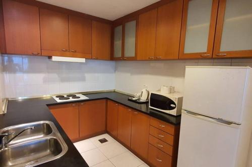 una cucina con armadi in legno e frigorifero bianco di Gateway Suite Cozy Dream Home for Nature Lover 8A a Kuching