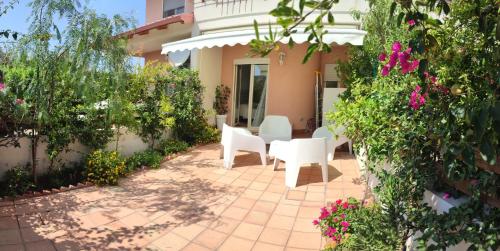 un patio con sedie bianche e fiori di fronte a una casa di Le Torrette di Anna - Tropea a Briatico