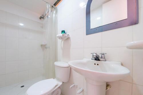 a white bathroom with a toilet and a sink at Ayenda Ambeima in Ibagué