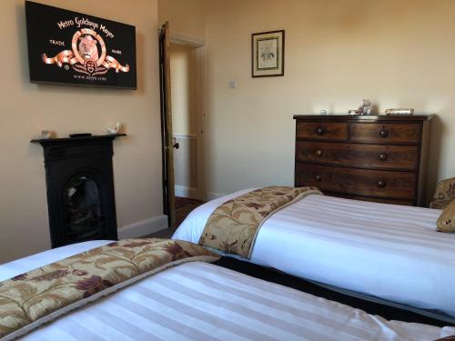 a bedroom with two beds and a dresser and a fireplace at Formby Guest House in Formby