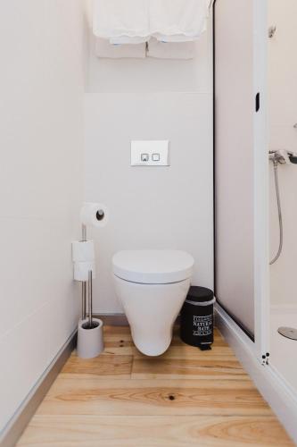 a white toilet in a bathroom with a wooden floor at Jaca Hostel Funchal in Funchal