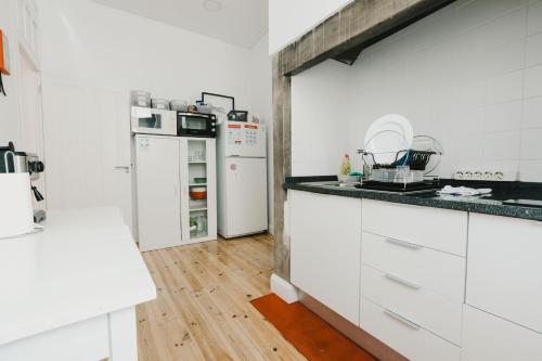 een keuken met witte apparatuur en een houten vloer bij Jaca Hostel Funchal in Funchal