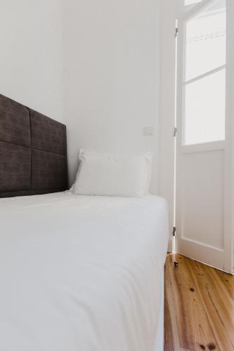 a bedroom with a white bed and a window at Jaca Hostel Funchal in Funchal