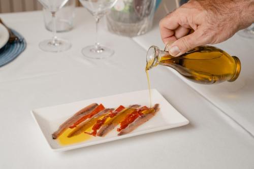 a person is pouring mustard on a plate of food at Luxmar Apartaments in Benidorm
