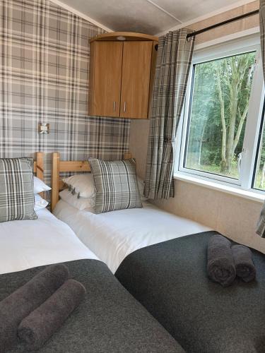 two beds in a small room with a window at Percy Wood Lodges with Hot Tubs in Swarland