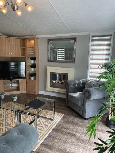 a living room with a couch and a fireplace at Percy Wood Lodges with Hot Tubs in Swarland