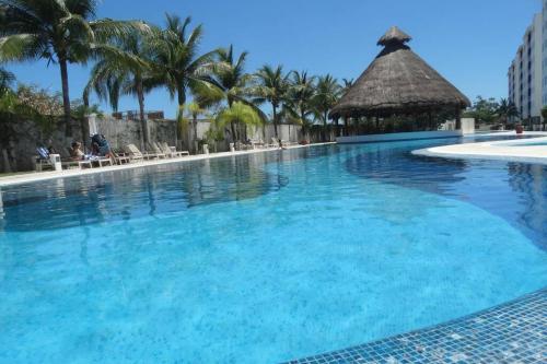 a large swimming pool with palm trees and a gazebo at Yikal Suites by Andiani Travel in Cancún