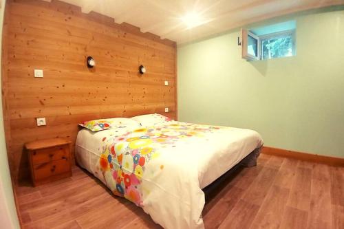 a bedroom with a bed with a wooden wall at Les berges du Doron in Planay