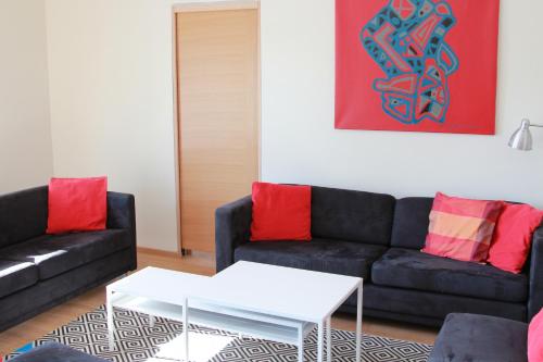 sala de estar con sofá negro y almohadas rojas en Papli Apartments en Pärnu