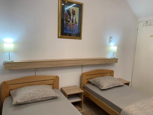 two beds in a room with two lamps on the wall at Guesthouse Vladimir & Ana in Pančevo