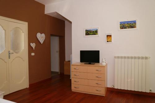 a bedroom with a television on a dresser with a door at La Casetta di Renato in Mormanno