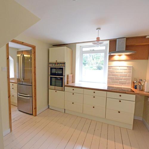 a large kitchen with white cabinets and a window at Rounceval House in Chipping Sodbury