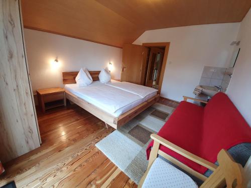 ヘルマゴルにあるFerienhaus Ball - Kometterhofのベッド1台と赤い椅子が備わる小さな客室です。