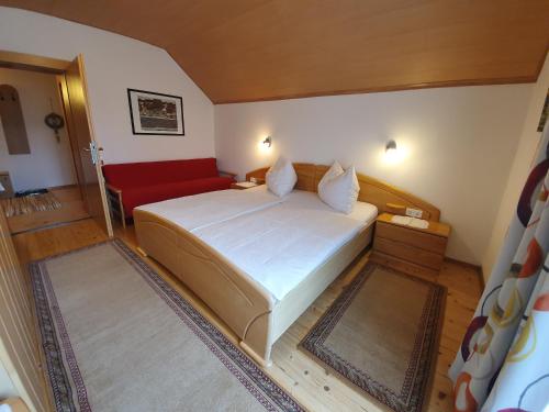 a bedroom with a large bed and a red couch at Ferienhaus Ball - Kometterhof in Hermagor