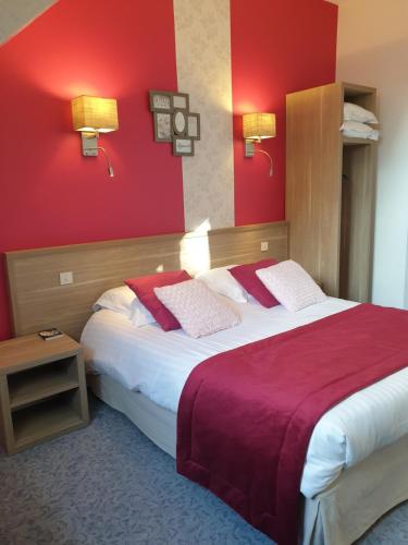 a hotel room with a large bed with red walls at Hôtel Le Rohan Charme et Caractère in Pontivy