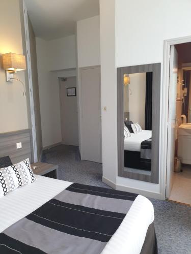 a hotel room with two beds and a mirror at Hôtel Le Rohan Charme et Caractère in Pontivy