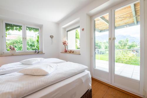 a white bedroom with a bed and windows at Ludwigschlössl in Garmisch-Partenkirchen