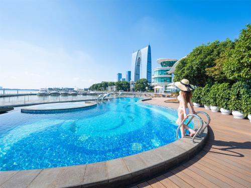 a woman in a hat is standing next to a swimming pool at Crowne Plaza Suzhou by IHG in Suzhou