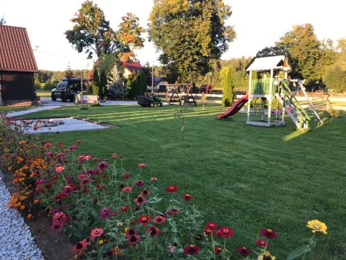 a park with a playground with a slide and flowers at Leśny Zakątek Uroczysko in Rychtal