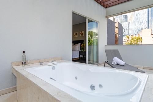 a bath tub in a bathroom with a large window at Suites Giorgio in Mexico City
