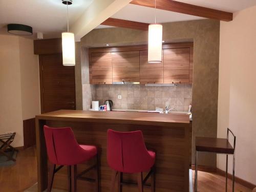 a kitchen with red chairs and a bar with a sink at Apartment B331 - Aparthotel Vucko Private host in Jahorina