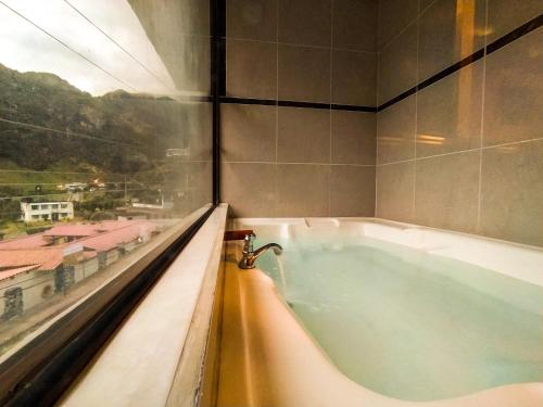 a bath tub in a room with a window at Hotel COTURPA in Papallacta