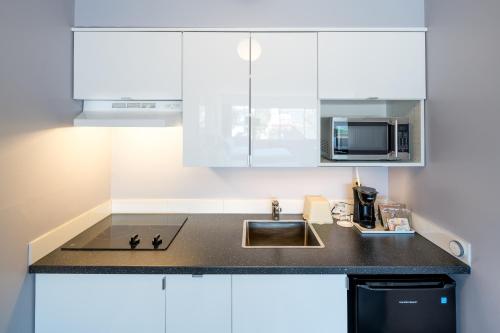 a kitchen with white cabinets and a sink at Cassandra Hotel in Vancouver