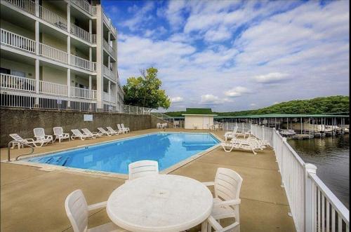 a swimming pool with a table and chairs next to a building at Family Fun Lakefront Condo at Parkview Bay in Osage Beach