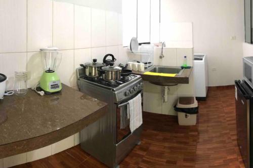 uma cozinha com um fogão e um lavatório com panelas e frigideiras em 200. Hermoso Departamento con Servicios Incluidos en Chorrillos em Lima