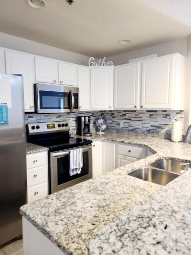 a kitchen with white cabinets and a granite counter top at Family Fun Lakefront Condo at Parkview Bay in Osage Beach
