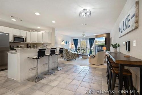 a kitchen with bar stools and a living room at Family Fun Lakefront Condo at Parkview Bay in Osage Beach