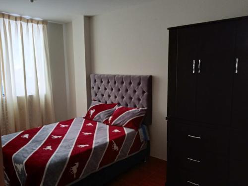 201 Departamento exclusivo en Chorrillos في ليما: غرفة نوم بسرير وبطانية حمراء ورمادية