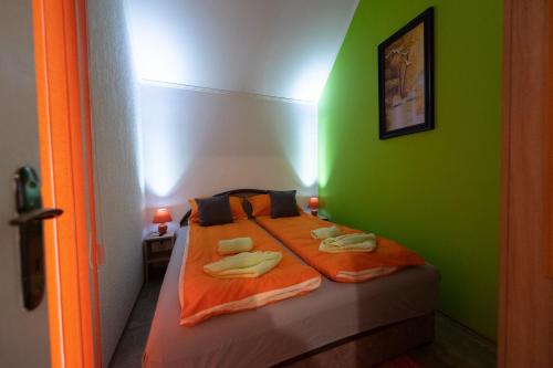 een groene slaapkamer met een bed met handdoeken erop bij Downtown 1 in Subotica