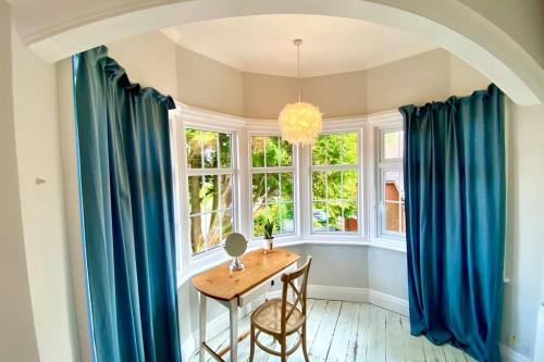 a dining room with blue curtains and a table and chairs at Cleveland House - Perfect for Beaches and Town. in Bournemouth